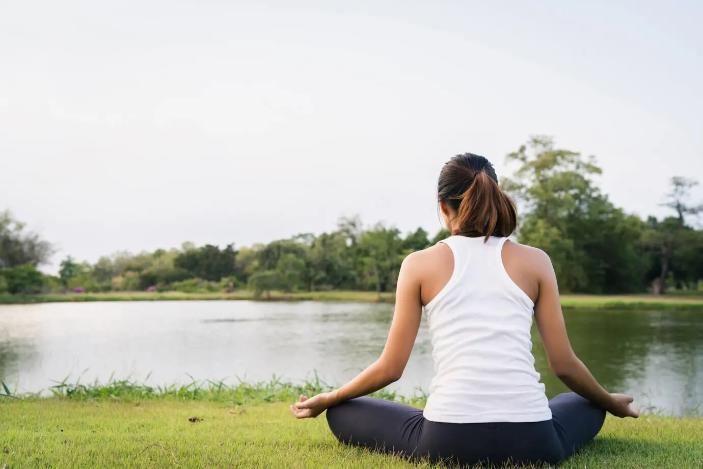 Jonge Aziatische vrouw doet yoga in de buitenlucht, blijft kalm en mediteert tijdens het beoefenen van yoga.
